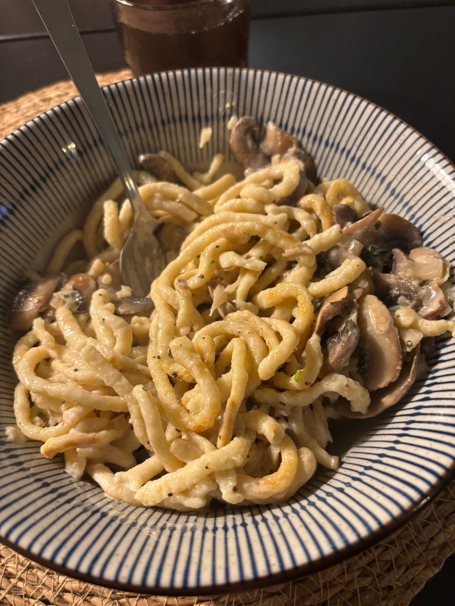 Goldgelbe Spätzle mit cremiger Champignon-Rahmsauce in einer tiefen Schüssel, garniert mit frischer Petersilie